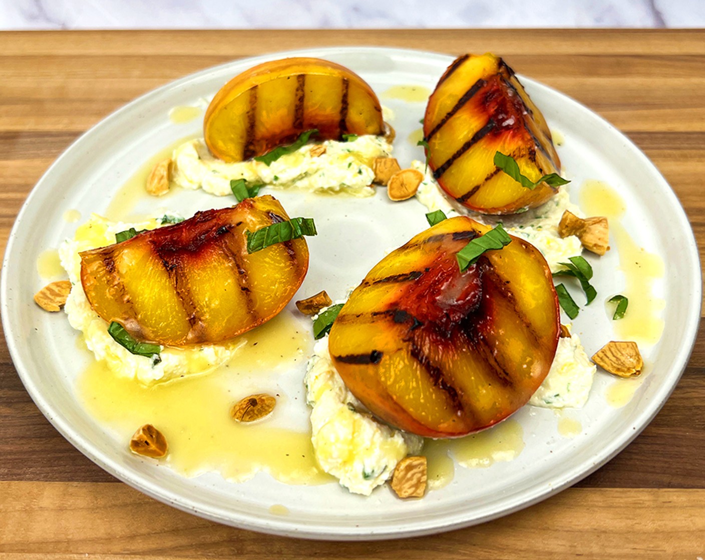 step 4 Dollop spoonfuls of the citrus herb ricotta on a plate, place the grilled peach slices in the ricotta and drizzle with the Balsamic Reduction (as needed). Scatter the Marcona Almonds (3 Tbsp) across the plate and garnish with Fresh Basil (1 bunch) and a sprinkle of Sea Salt Flakes (as needed).