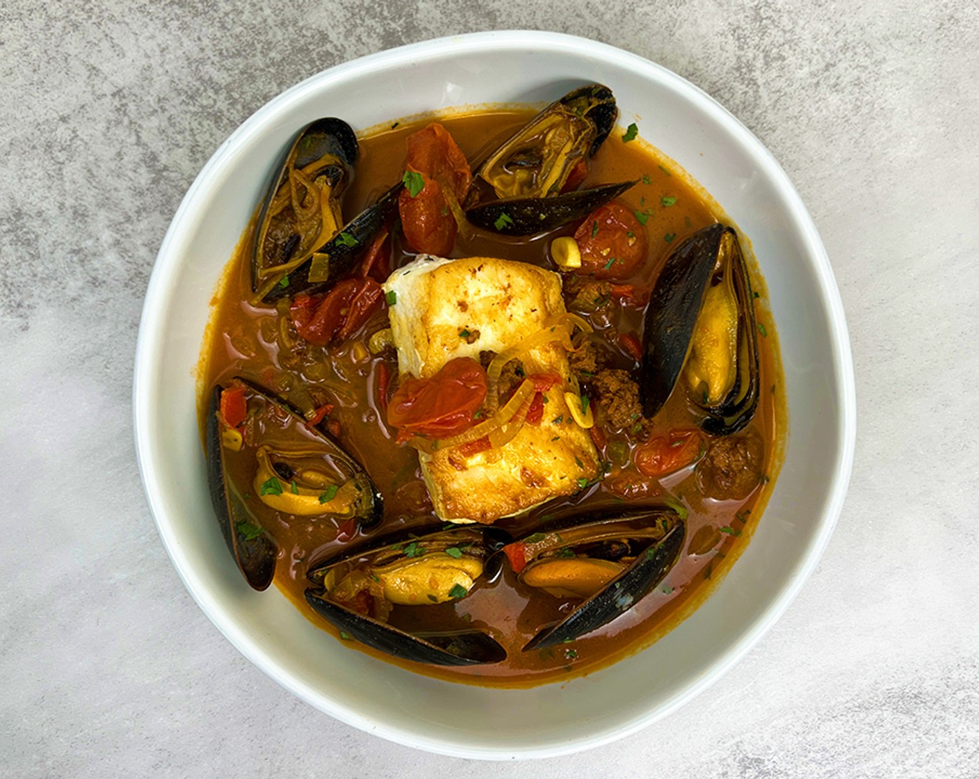 step 5 Pour the stewed mussels and broth into a bowl and place the halibut in the middle. Top with the seared prawn and chopped parsley.