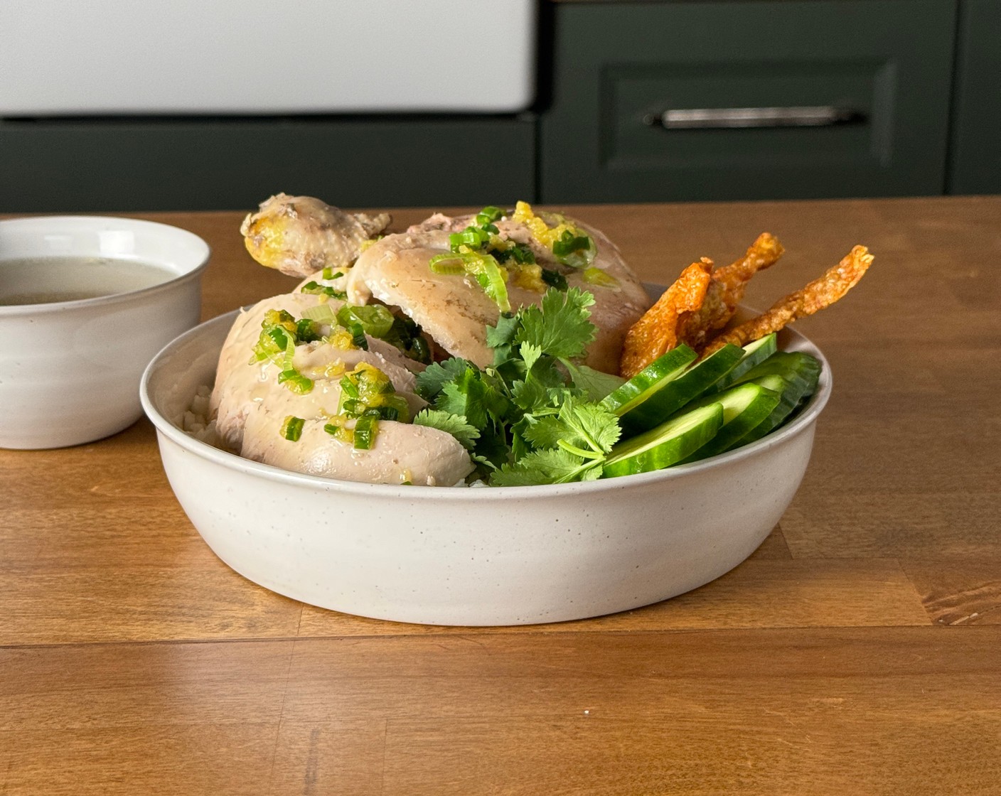 step 4 In serving bowls, layer rice, poached chicken, sliced Cucumbers (2), Fresh Cilantro (1/2 bunch), and drizzle with scallion oil and top with crispy chicken skin. Serve with a small bowl of the chicken broth on the side.