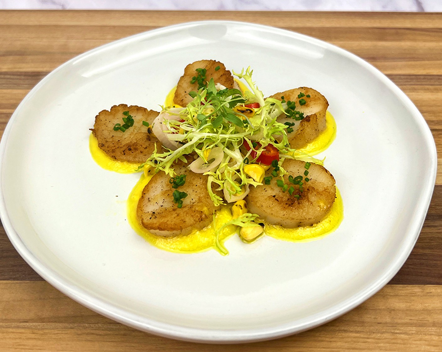 step 13 Place 5 small spoonfuls of the corn puree in a circle around the plate. Place one scallop, seared side up on each puree. In the middle of the plate, place the salad and top with Arugula (1 bunch) and Fresh Chives (1 bunch).