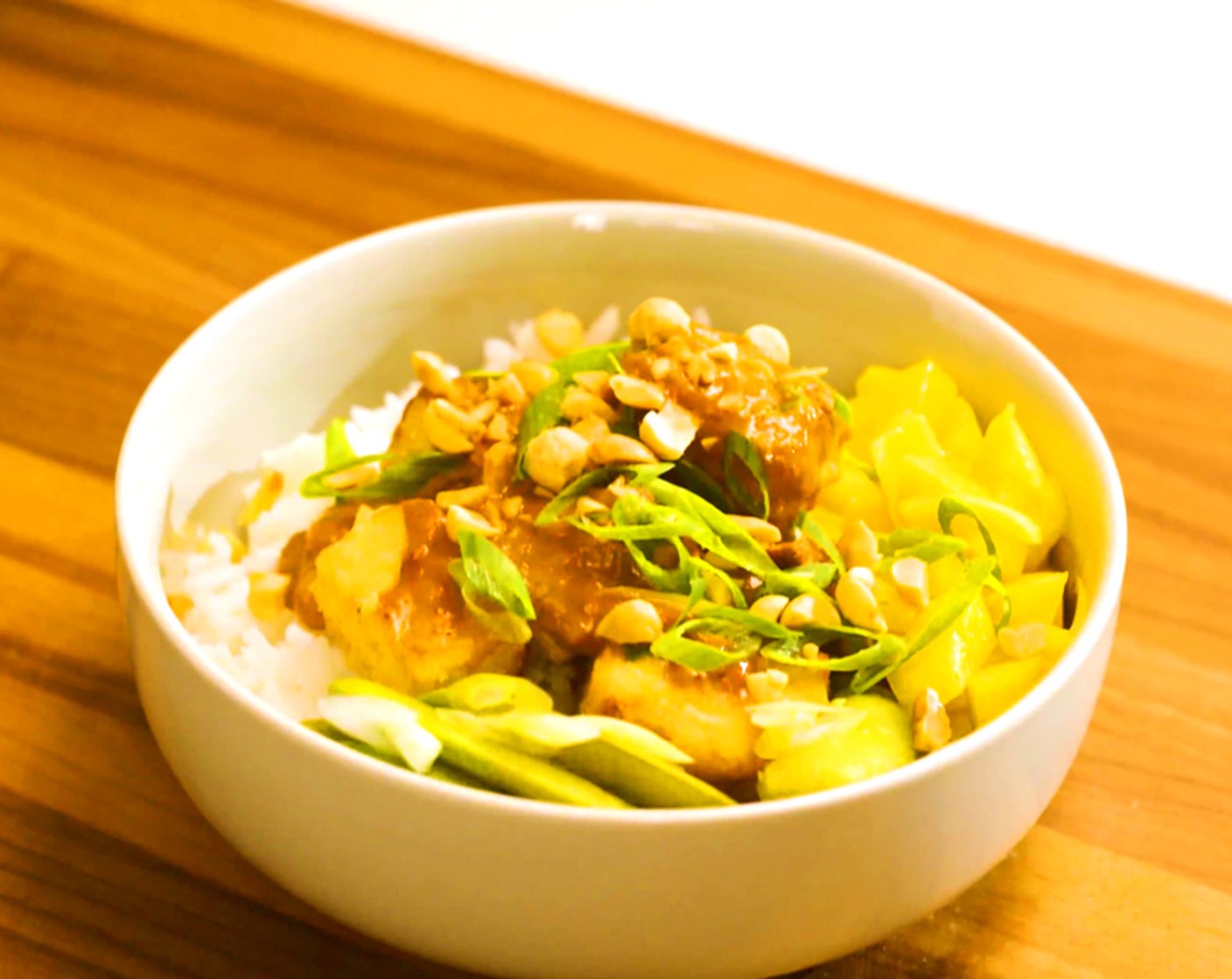 step 5 Assembly: Serve the crispy tofu over steamed White Rice (to taste) and drizzle with the peanut sauce. Add the pickled snap peas, diced Mangoes (to taste), scallion greens, Salted Peanuts (to taste), and Limes (to taste) wedges.