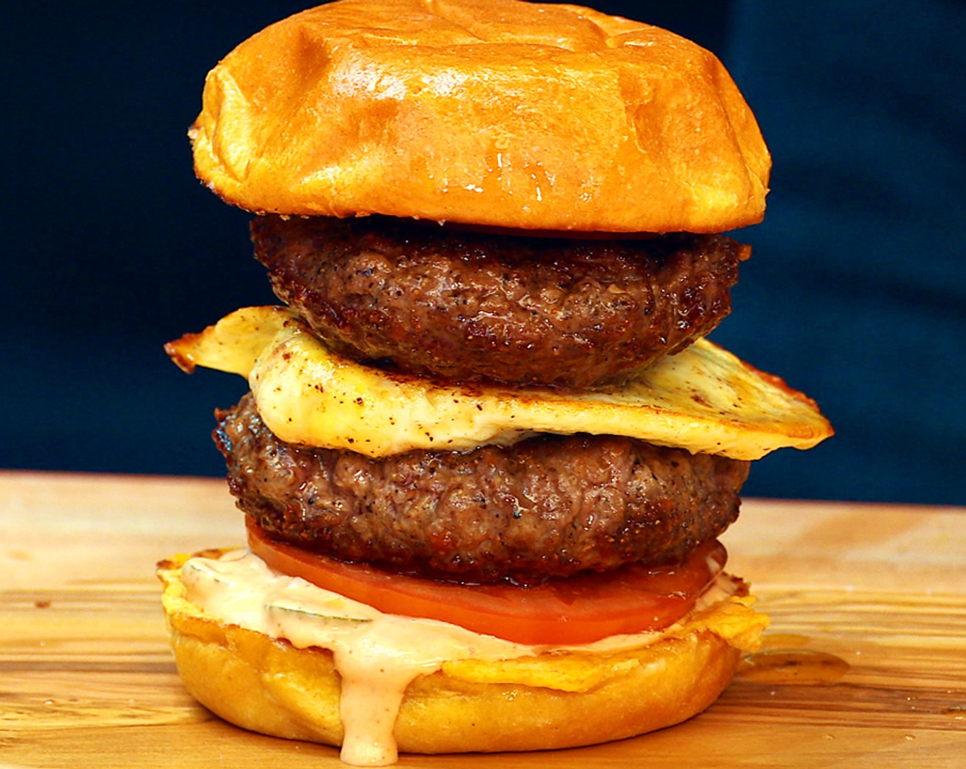 step 12 Assemble the burger: Place one bottom bun on a plate, spread the sauce across the bun, then add a slice of Beefsteak Tomato (1) and season the tomato with salt and pepper. Layer one patty onto the tomato then place the egg on top, followed by the second patty, Red Onion (1), and more sauce. Place the top bun on and repeat with the remaining ingredients.